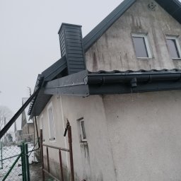 Usługi Blacharsko-Dekarskie Łukasz Siwkowski - Dom jednorodzinny z nowym, ciemnoszarym orynnowaniem i obróbkami blacharskimi, widoczne rusztowanie i narzędzia pracy na pierwszym planie.