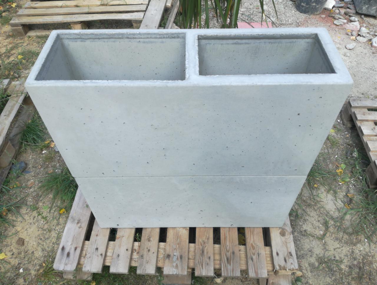 Szara, betonowa donica dwukomorowa, stojąca na drewnianej palecie, widok z góry, surowy styl.