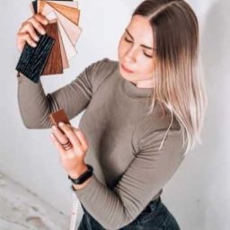 BAJON DESIGN - Kobieta w Poznaniu przegląda próbki materiałów wykończeniowych, trzymając wachlarz drewnianych i czarnych paneli w dłoni.