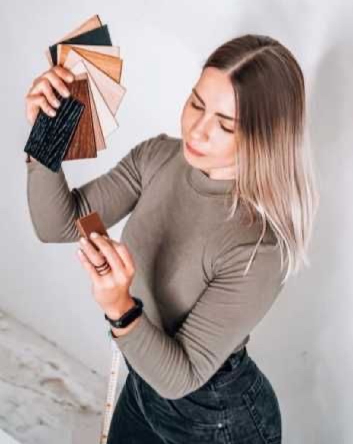 Kobieta w Poznaniu przegląda próbki materiałów wykończeniowych, trzymając wachlarz drewnianych i czarnych paneli w dłoni.