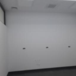 Remonter - Pusta, pomalowana na biało ściana z trzema otworami na gniazdka elektryczne, widok z dołu, czarna listwa przypodłogowa.