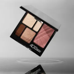Paleta do makijażu z różnymi odcieniami, unosząca się nad powierzchnią wody, z widocznym odbiciem i napisem '40 years of celebrating your beauty'.