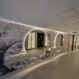 KPT Piotr - Tapeta imitująca marmur z okrągłymi lustrami podświetlonymi LED, zamontowanymi na szafkach. Nowoczesny design wnętrza, eleganckie wykończenie ściany.