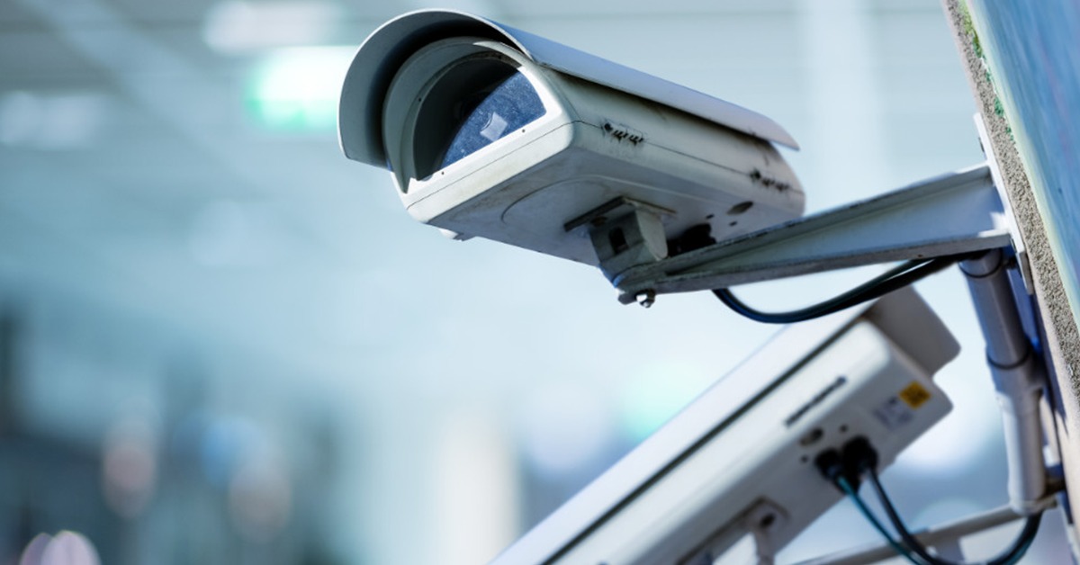 Dwie kamery przemysłowe zamontowane na ścianie budynku, widoczne przewody zasilające i elementy mocujące.