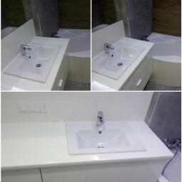 Usługi hydrauliczne - Biała umywalka z chromowaną baterią zamontowana na blacie w łazience w Warszawie, widoczne włączniki światła na ścianie i fragment wanny.