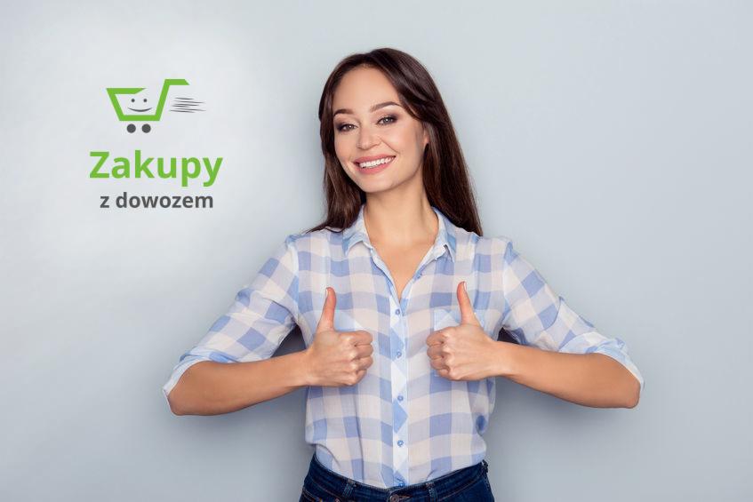 Uśmiechnięta brunetka w koszuli w kratę, pokazująca kciuki w górę obok logo 'Zakupy z dowozem' z zielonym wózkiem.