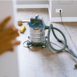 Nimboos - Przemysłowy odkurzacz na drewnianej podłodze, z widoczną szczotką i ręką w kadrze, sugerujący sprzątanie po remoncie.