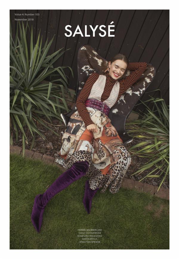 Okładka magazynu modowego 'Salysé' z modelką w wzorzystej sukience, brązowo-pomarańczowym golfie i fioletowych kozakach, siedzącą na krześle obitym skórą w ogrodzie, na tle drewnianego płotu...
