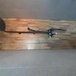 Czarny zestaw natryskowy z deszczownicą i baterią termostatyczną zamontowany na ścianie wyłożonej panelami imitującymi drewno w wyremontowanej łazience.