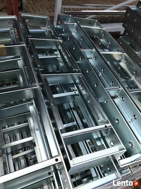 Stos nowych, metalowych drabin budowlanych, ułożonych równolegle, widocznych z bliska pod kątem.