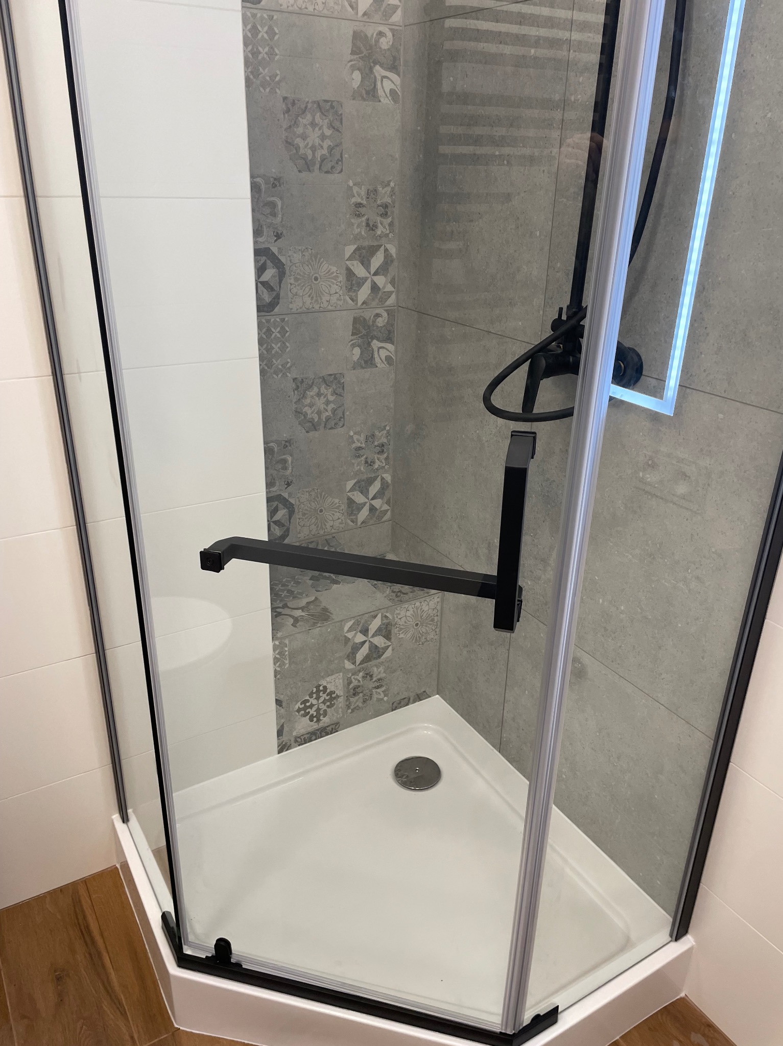 Nowoczesna kabina prysznicowa z czarnymi detalami i wzorzystymi płytkami w tle, Suchy Dąb. Wykończenie łazienki z dbałością o szczegóły.