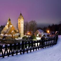 Kodama Foto - Karpacz, Kościół Wang w zimowej scenerii, oświetlony nocą, widok zza drewnianego płotu.