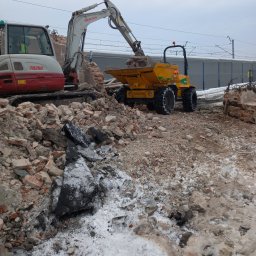 BET GROUNDWORKS SPÓŁKA Z OGRANICZONĄ ODPOWIEDZIALNOŚCIĄ - Rozbiórka ceglanego budynku z użyciem koparki Takeuchi i wywrotki. Gruz i śnieg na ziemi. Widoczne fragmenty zniszczonej konstrukcji.