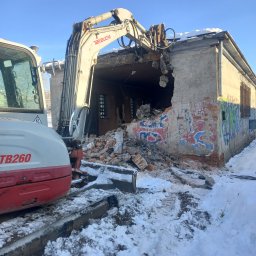 BET GROUNDWORKS SPÓŁKA Z OGRANICZONĄ ODPOWIEDZIALNOŚCIĄ - Rozbiórka budynku z graffiti w zimowej scenerii. Koparka Takeuchi TB260 w trakcie pracy, gruz leży na śniegu. Widoczne zniszczone ściany i fragment dachu.