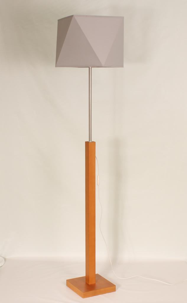Lampa podłogowa z drewnianą podstawą i szarym, geometrycznym abażurem na tle jasnej ściany.