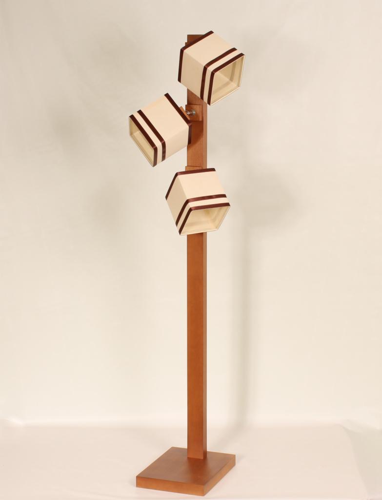 Stojąca lampa podłogowa z trzema kwadratowymi abażurami w kolorze kremowym z brązowymi obwódkami, umieszczonymi na brązowym drewnianym słupku z kwadratową podstawą.