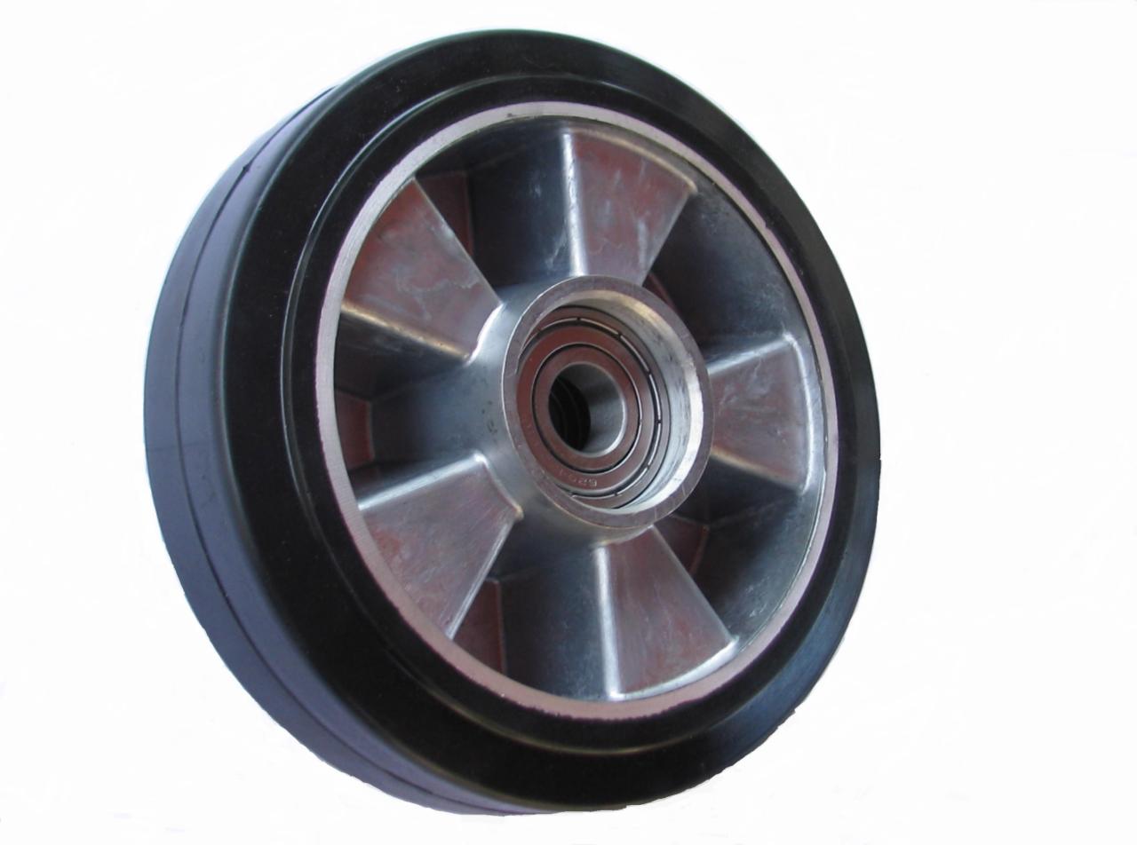 Koło wózka paletowego ręcznego z czarną gumową oponą i srebrną felgą z widocznym łożyskiem kulkowym na białym tle.