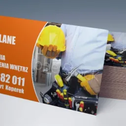 Stos wizytówek firmy budowlanej z usługami elewacyjnymi, ogrodzeniami i wykończeniami wnętrz, prezentujący zbliżenie na robotnika w kasku i z narzędziami.