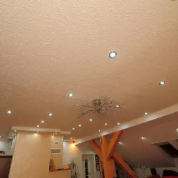 Sufit z zamontowanymi punktowymi źródłami światła LED i dekoracyjnym żyrandolem w stylu gałęzi, wykonany w domu w Zielonej Górze.