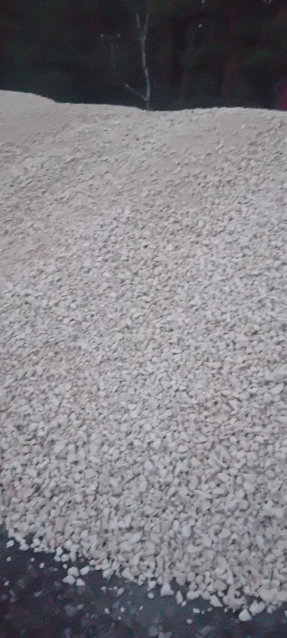 Biały żwir równomiernie rozłożony na powierzchni, z ciemnym tłem w górnej części kadru. Widok z góry, ukazujący strukturę materiału.