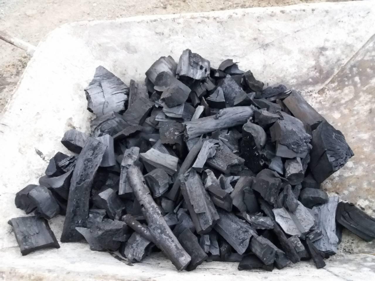 Kupa pociętego na kawałki czarnego drewna w taczce o betonowym wykończeniu.