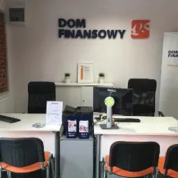 Biuro Domu Finansowego z dwoma stanowiskami pracy, monitorami Dell, krzesłami z pomarańczowymi oparciami, ścianą z cegły i logo firmy na ścianie oraz bannerem reklamowym.
