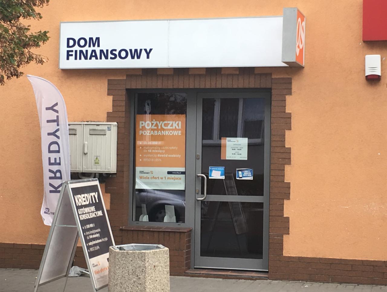 Fasada budynku 'Dom Finansowy' z szyldem nad wejściem, obok reklama kredytów gotówkowych i pozabankowych, flaga reklamowa. Widoczne informacje o RRSO i maksymalnym okresie spłaty.