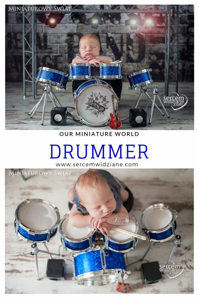 Śpiący noworodek oparty na miniaturowej perkusji z niebieskimi bębnami, mała gitara w tle, studyjne oświetlenie i dekoracje imitujące scenę koncertową.