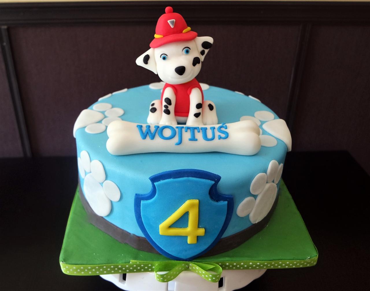 Tort urodzinowy dla czterolatka z figurką psa w strażackim stroju i imieniem 'Wojtuś' na kości z lukru.