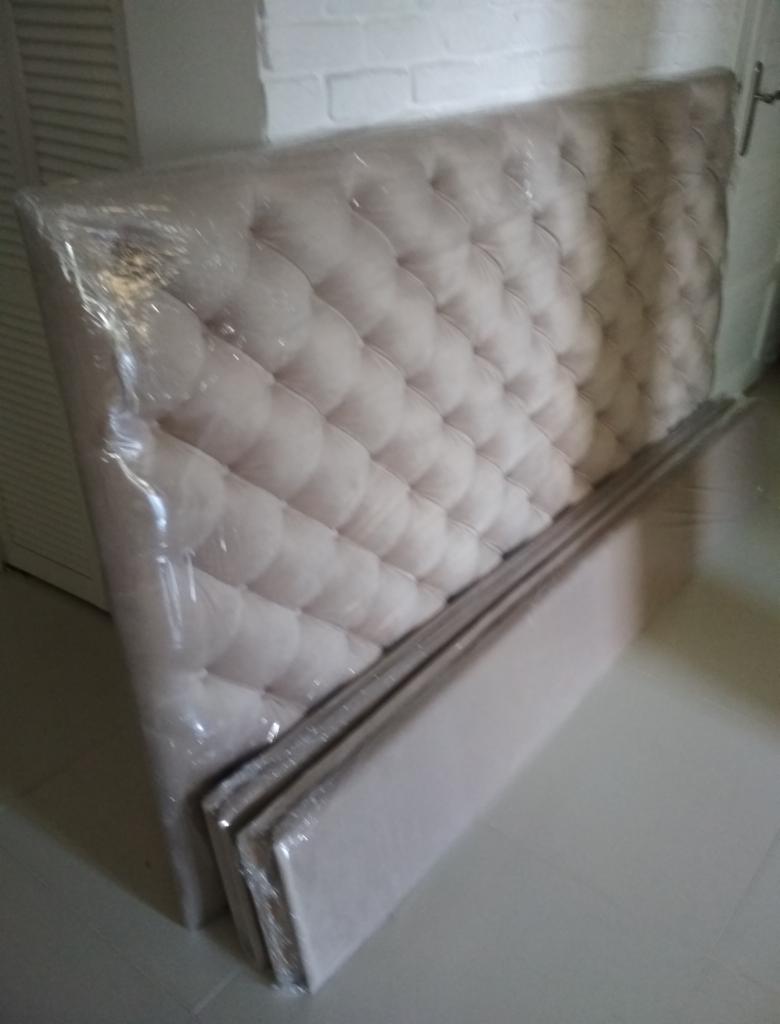 Tapicerowane wezgłowie łóżka w folii ochronnej, przygotowane do transportu w Warszawie, z widocznym pikowaniem i guzikami.