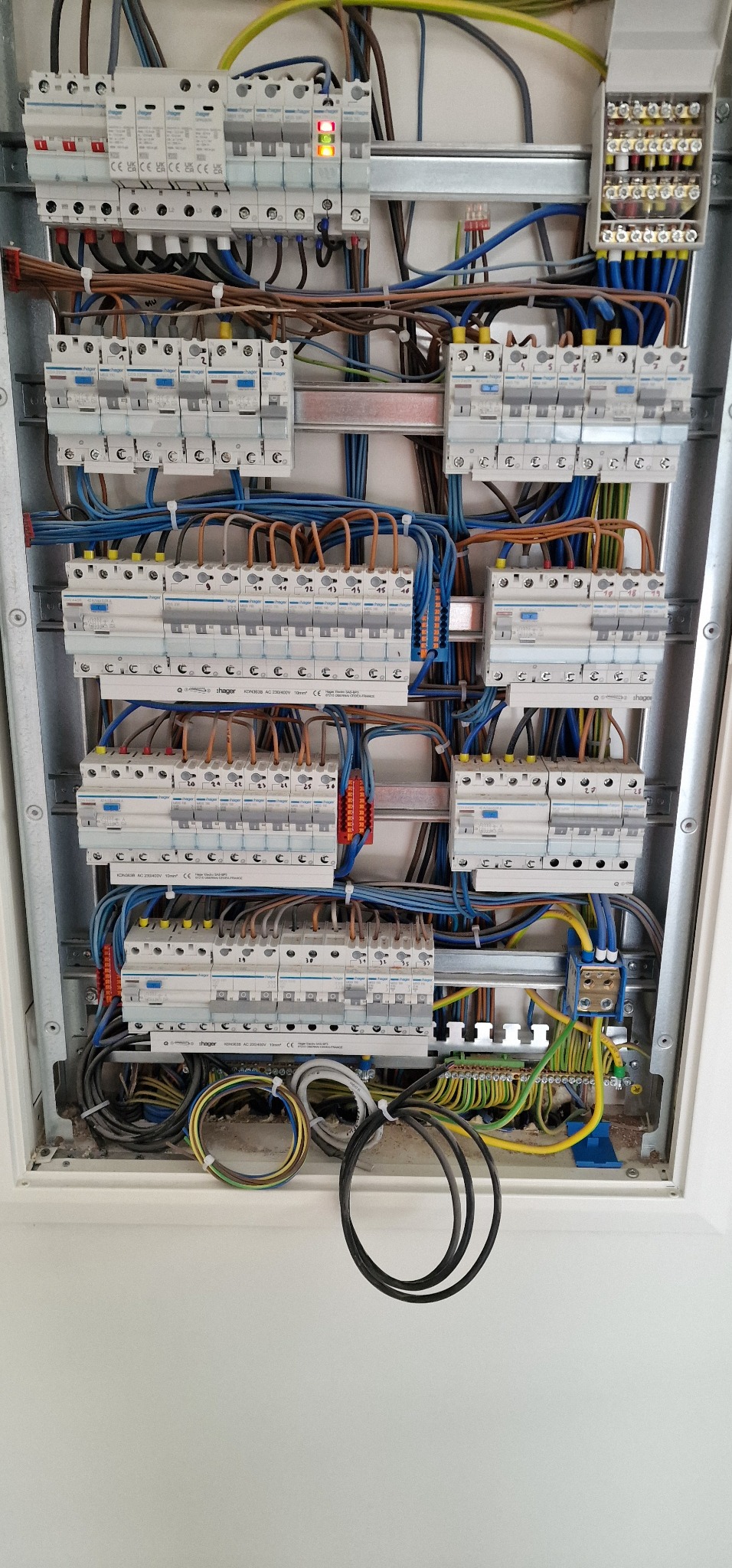 Rozdzielnica elektryczna z zainstalowanymi bezpiecznikami i okablowaniem. Widoczne przewody w różnych kolorach oraz elementy montażowe.