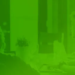 Zespół programistów pracuje przy laptopach w biurze, jeden z nich ma na uszach słuchawki, a inny słucha muzyki przez słuchawki douszne.