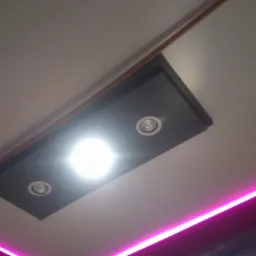 Biały sufit z podwieszanym, czarnym elementem z dwoma punktowymi lampami halogenowymi; dodatkowo dekoracyjne oświetlenie LED w kolorach różowym i zielonym.