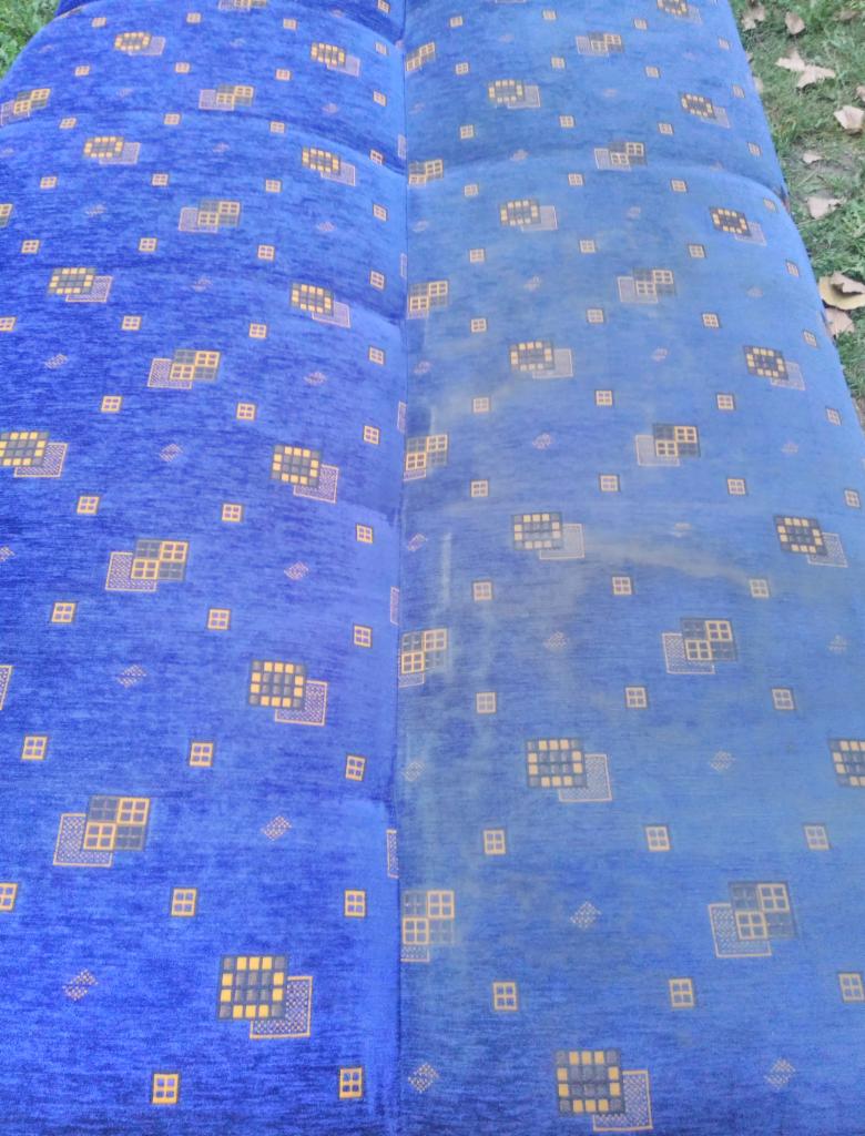 Połowa niebieskiej kanapy z geometrycznym wzorem jest wyraźnie czystsza od drugiej, brudniejszej połowy, co demonstruje efekt czyszczenia tapicerki.