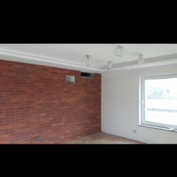 Mar-bud - Wnętrze pokoju po remoncie: ściana z cegły dekoracyjnej, pomalowana ściana, sufit z oświetleniem punktowym.