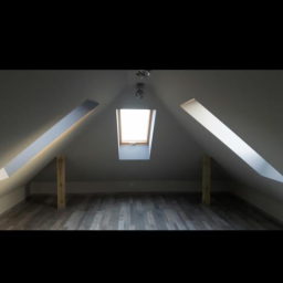 Mar-bud - Poddasze z oknem dachowym i drewnianą podłogą, widoczne drewniane podpory konstrukcyjne i lampa sufitowa.