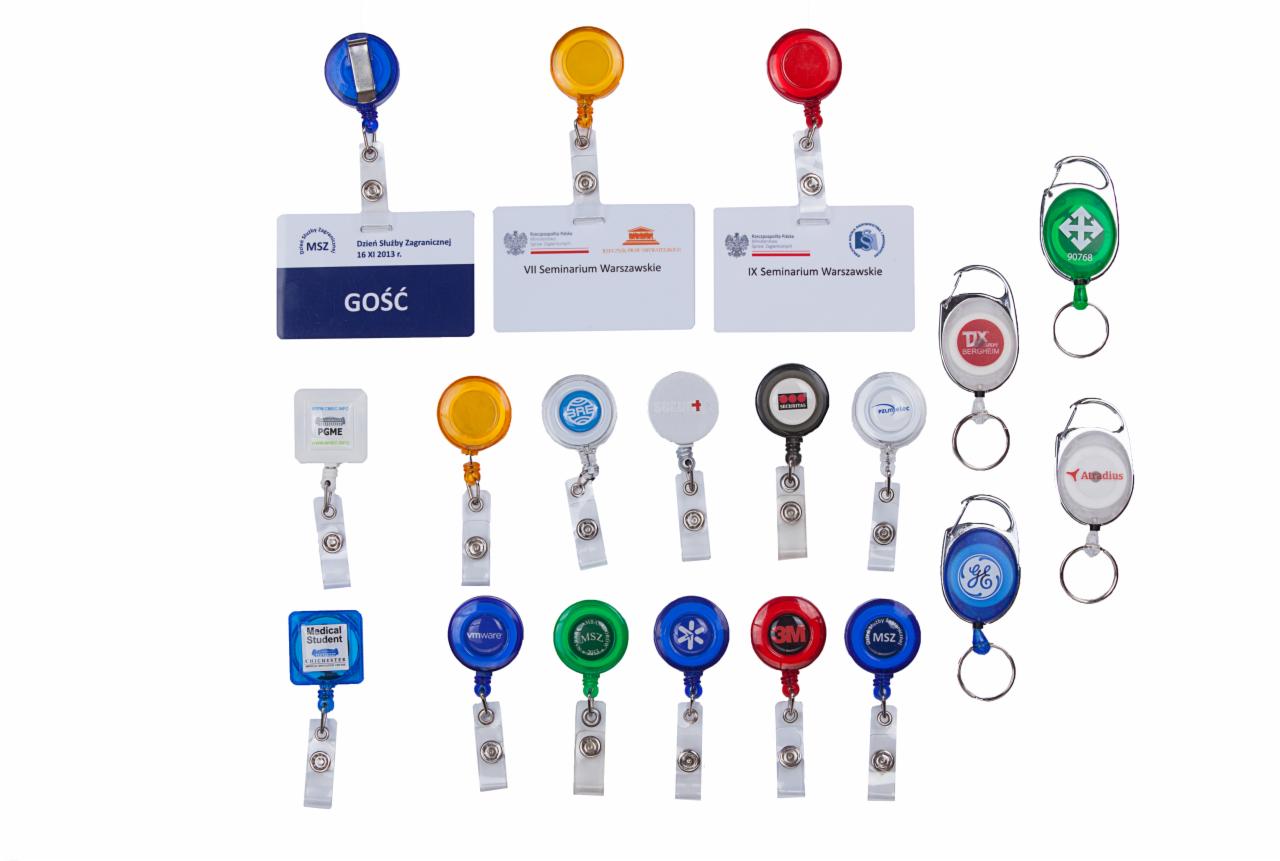 Kolekcja identyfikatorów i smyczy z logo firm i instytucji, niektóre z identyfikatorami gościa i nazwami seminariów, na białym tle.