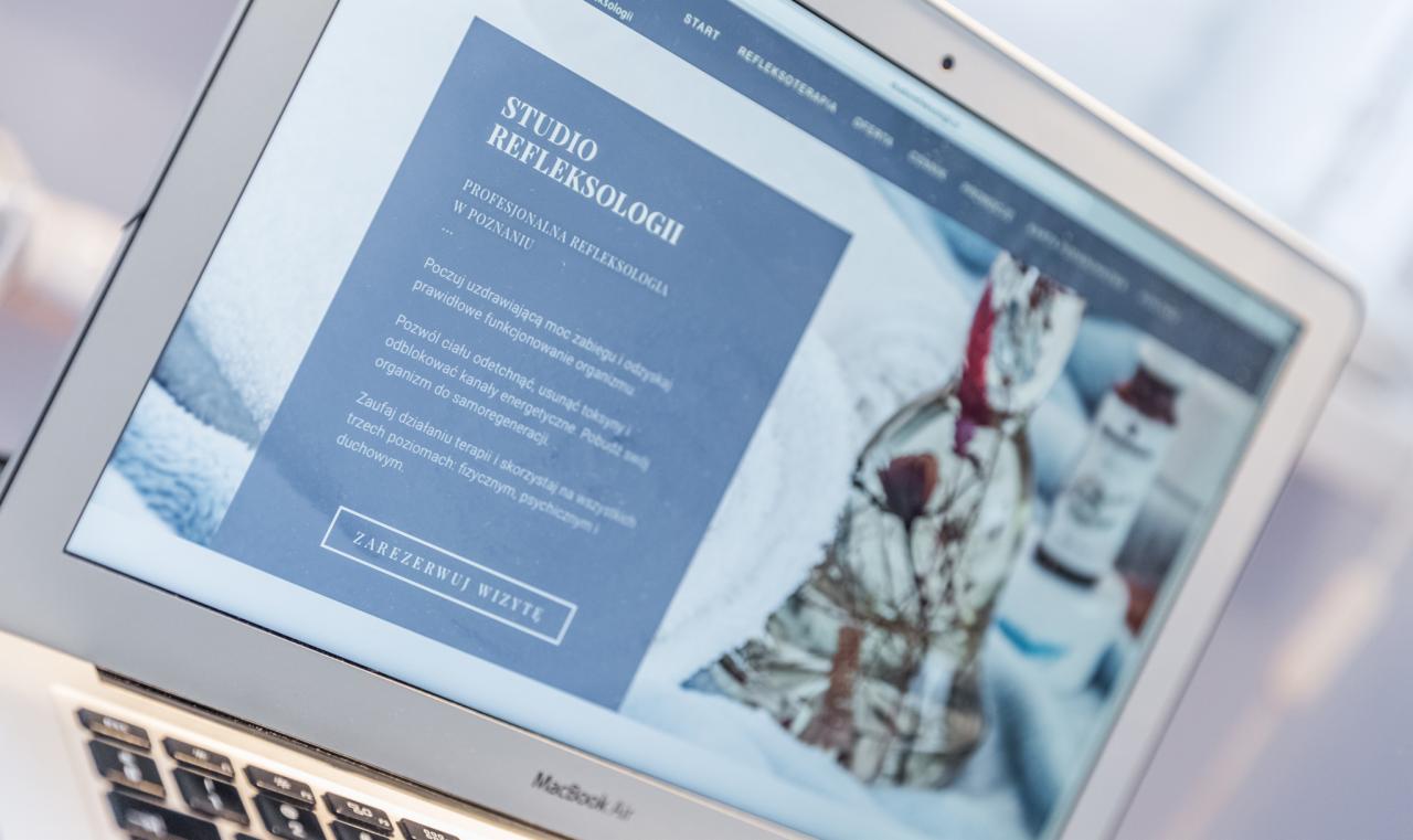 Ekran laptopa MacBook Air wyświetlający stronę internetową studia refleksologii w Poznaniu, z tekstem zachęcającym do rezerwacji wizyty i zdjęciem w tle prezentującym produkty do pielęgnacji.