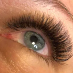 Zbliżenie na oko z gęstymi, czarnymi sztucznymi rzęsami w Kuklówka Radziejowicka, z delikatnym odblaskiem światła na tęczówce.