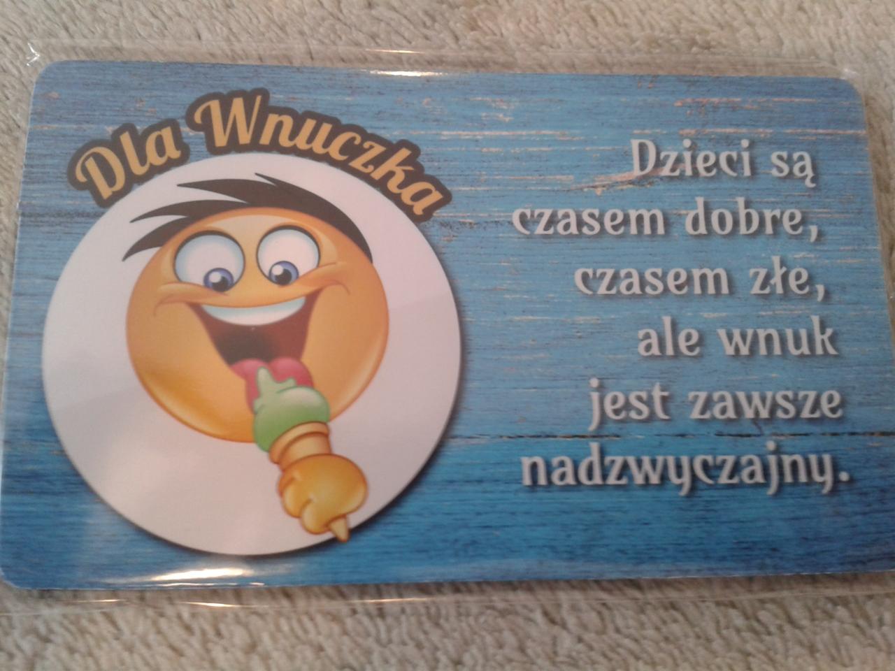 Pamiątka dla wnuczki z emotikonem jedzącym loda i tekstem o wyjątkowości wnuków na tle imitującym drewniane deski.