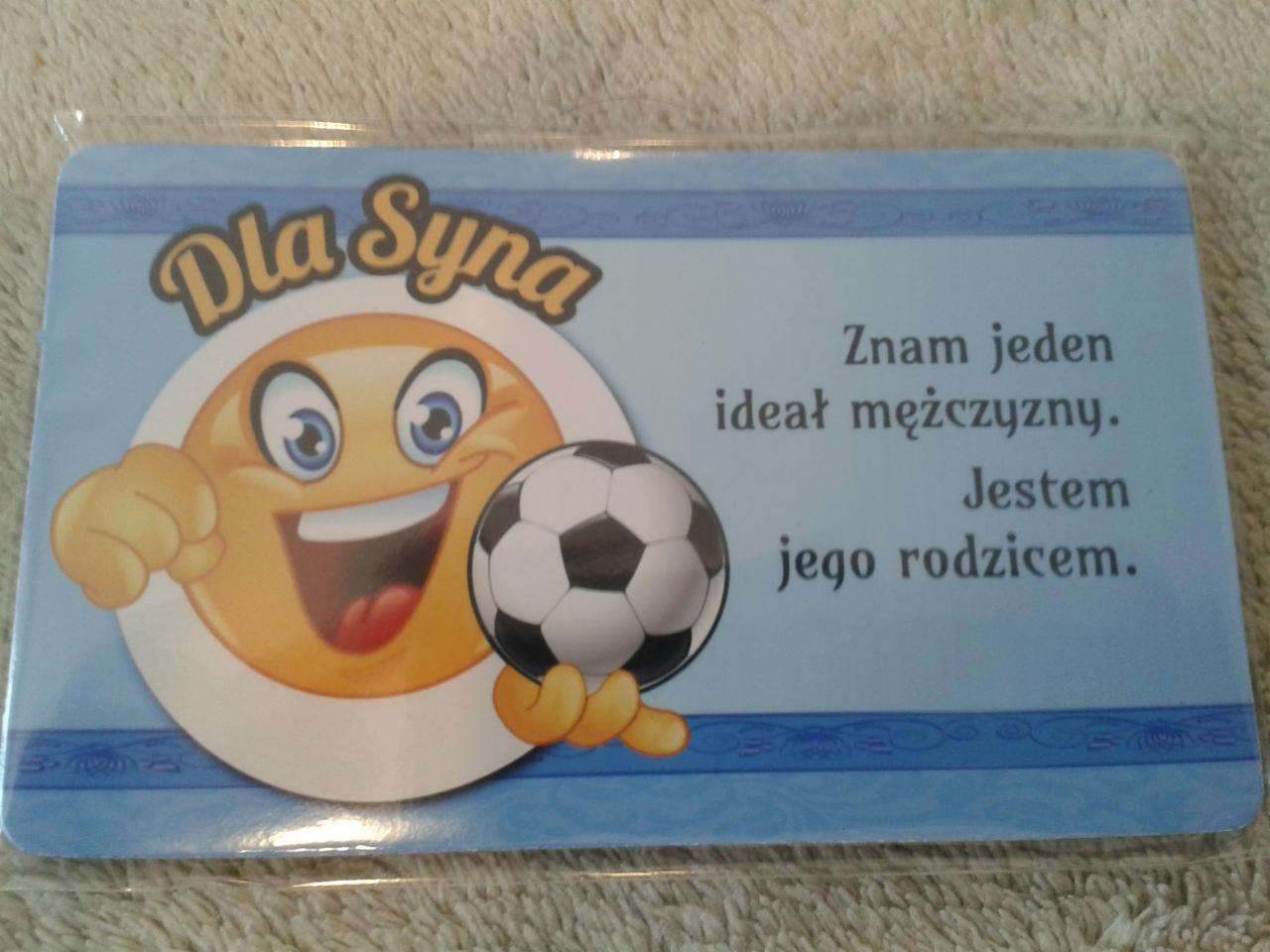 Karta prezentowa dla syna z uśmiechniętą emotikoną trzymającą piłkę nożną i tekstem 'Znam jeden ideał mężczyzny. Jestem jego rodzicem'.