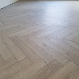 Ułożone panele podłogowe w jodełkę francuską, widok z góry, jasne drewno, świeżo po montażu, białe ściany, grzejnik na ścianie w tle.