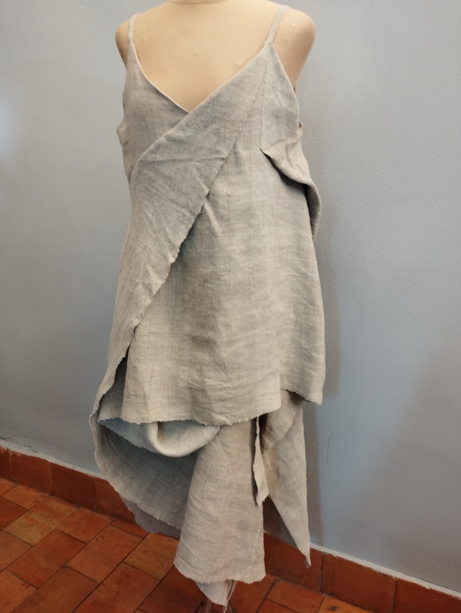 Linen dress prototype on a mannequin in a Lublin workshop, featuring raw edges and draped design.