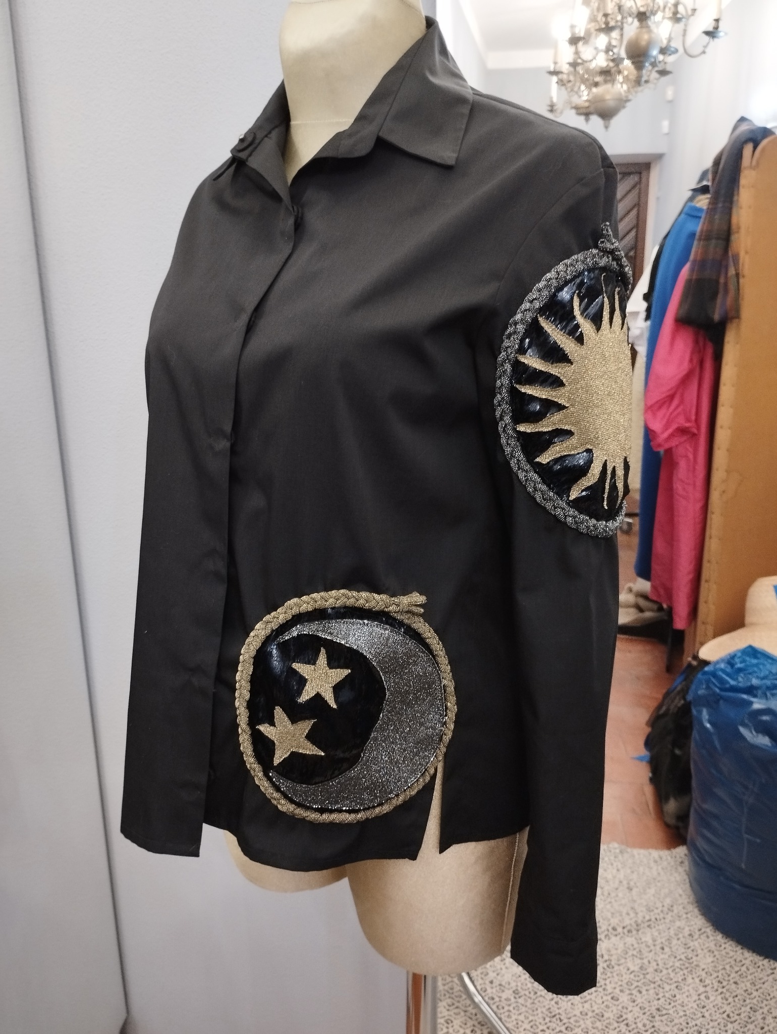 Czarna koszula damska z aplikacjami słońca i księżyca z gwiazdami, prezentowana na manekinie.