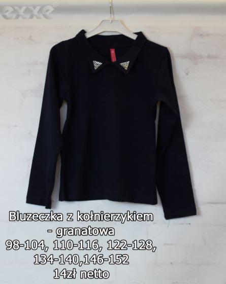 Granatowa bluzka z długim rękawem i ozdobnym kołnierzykiem z trójkątami z cekinami, wisząca na wieszaku na tle ściany z fakturą.