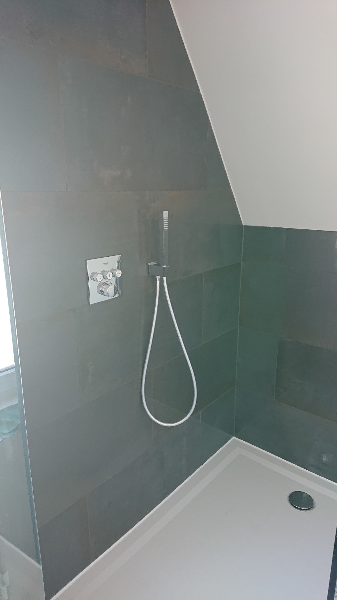 Kabina prysznicowa z szarymi płytkami i białą brodzikiem w łazience w Nowym Świętowie, widoczna bateria i słuchawka prysznicowa.