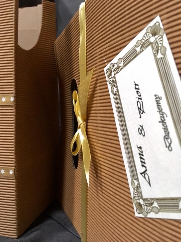 Dwa pudełka z tektury falistej, jedno z uchwytem i gwiazdkami, drugie z żółtą wstążką i ozdobną etykietą z napisem 'Anna & Piotr, Dziękujemy'