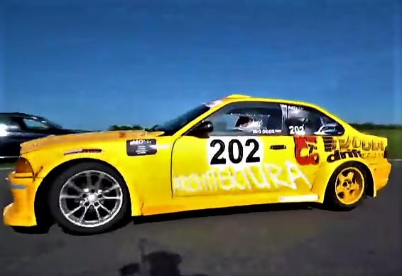 Żółty samochód driftingowy z numerem 202 i napisem 'ARCHITEKTURA' na boku, podczas jazdy na torze.