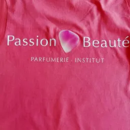 Różowa koszulka z białym nadrukiem 'Passion Beauté' i grafiką przypominającą płatek róży w kolorach różu i bieli, pod napisem 'PARFUMERIE - INSTITUT'.