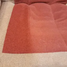 Fragment kanapy z widoczną różnicą w kolorze i czystości po wypraniu części tapicerki w odcieniach brązu i beżu.